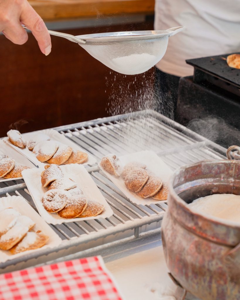 Poffertjes bestrooid met poedersuiker bij de kraam